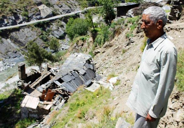 Shri Jagdish Sharma standing in front of the debris of his leftover house after the leakage tragedy