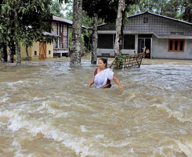 SWIRLING WATERS:A woman wades through flood water at a village in Sonitpur district of Assam on Wednesday. Nearly 65,000 people in over 155 villages across the State have been affected in the flood, following incessant rain.— PHOTO: PTI