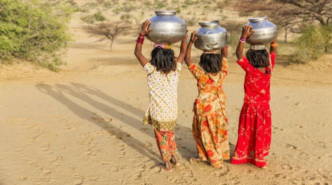 Indian little girls carrying on their heads water from well